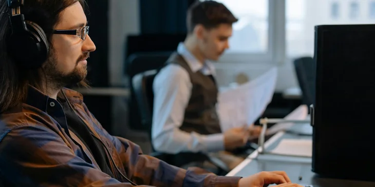 An IT auditor sitting at his workstation and reviewing the overall information system report.