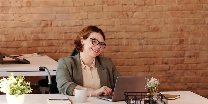 A woman smiling while using a laptop.