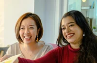 Zwei Frauen arbeiten lächelnd in eine Büro.