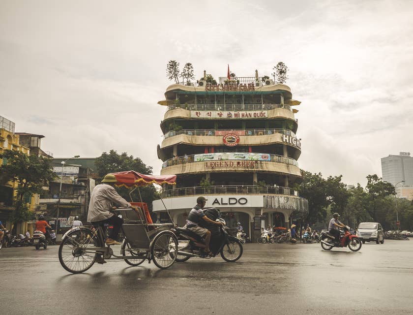 Hanoi street with mopeds, cars and cyclists driving past in Vietnam.