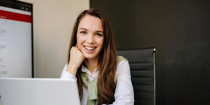 A woman sitting in a desk in front of a laptop.