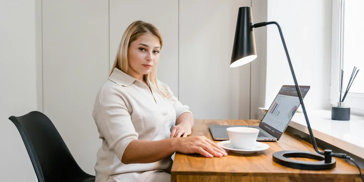 A woman sitting on a black chair in front of a laptop.