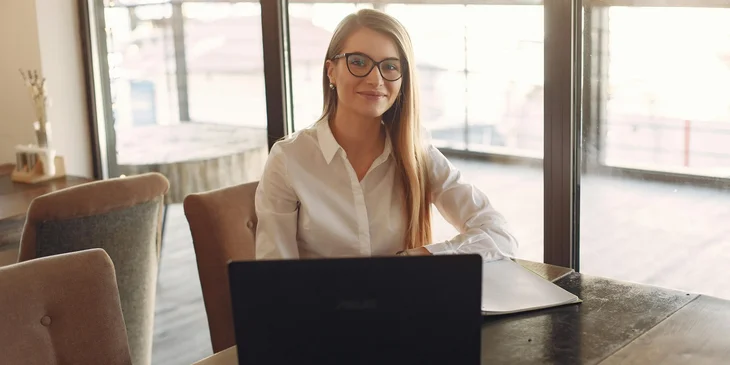 A woman in white polo shirt sitting in front of a laptop.