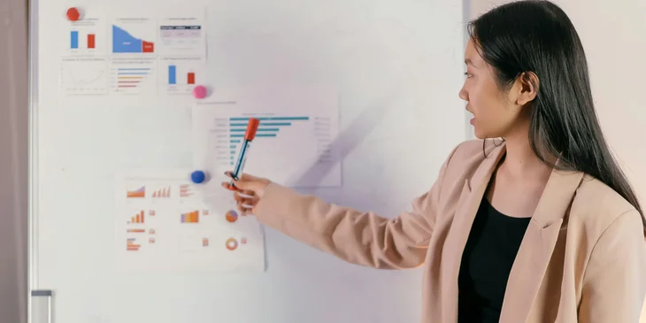 A woman presenting the latest market trends on a whiteboard.