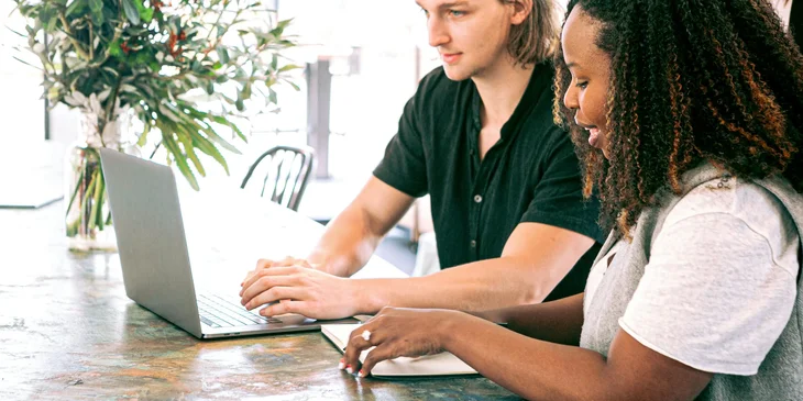 A man and a woman working together on a laptop.