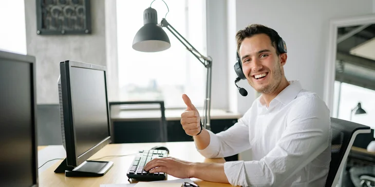 A man giving a thumbs-up while sitting at his work desk.