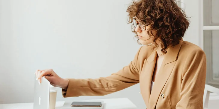 A woman opening a laptop on a desk.