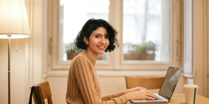 A woman working at her desk, smiling at the camera.