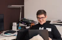 İş yerinde laptop kullanırken gülümseyen bir adam.