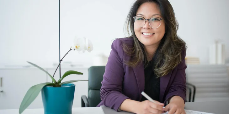 A woman sitting on a table with potted plant.