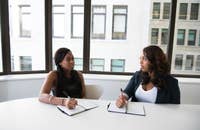 Deux femmes se préparant à poser des questions d'entretien d'embauche sur le leadership.