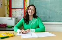 Una profesora sentada en el escritorio de su salón de clases.