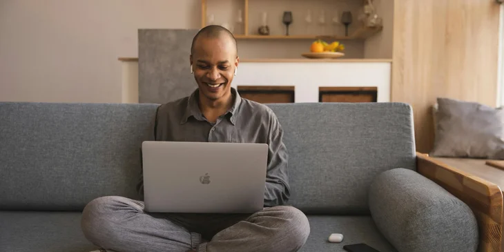 A man sitting on a sofa while using a laptop.