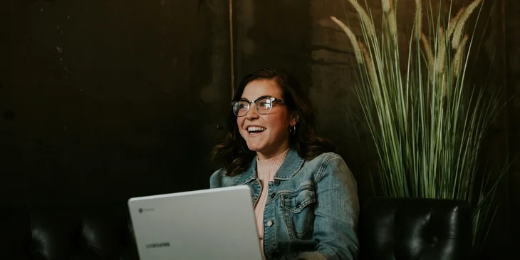A woman smiling while working on her laptop.