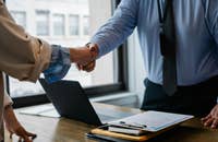 Due persone che si stringono la mano dopo che una di esse ha ricevuto una lettera di promozione.