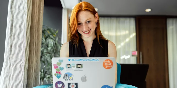 A woman working on a laptop in an office lobby.