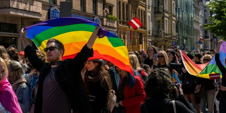 People attending a street parade and waving pride flags to raise awareness for the LGBTQ+ community.