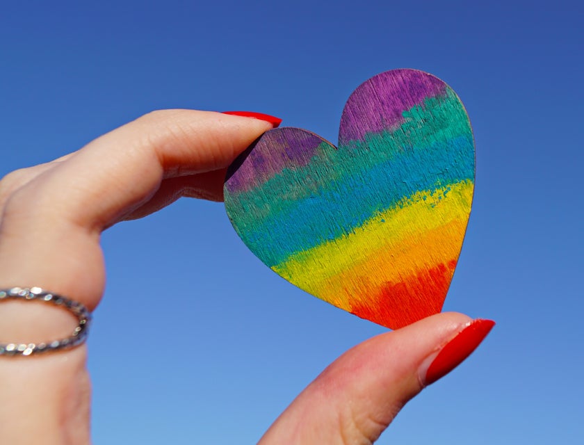 A person holding a multicolored heart-shaped card.