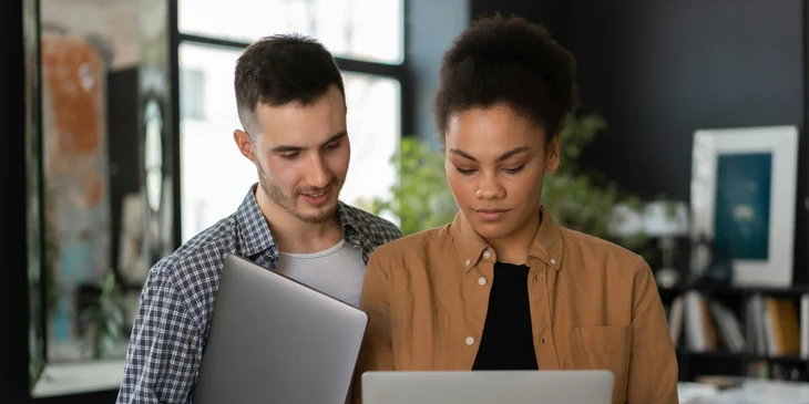 Two coworkers reviewing something on a laptop.