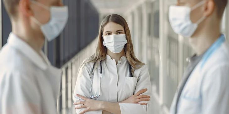 A woman in white coat wearing white face mask.