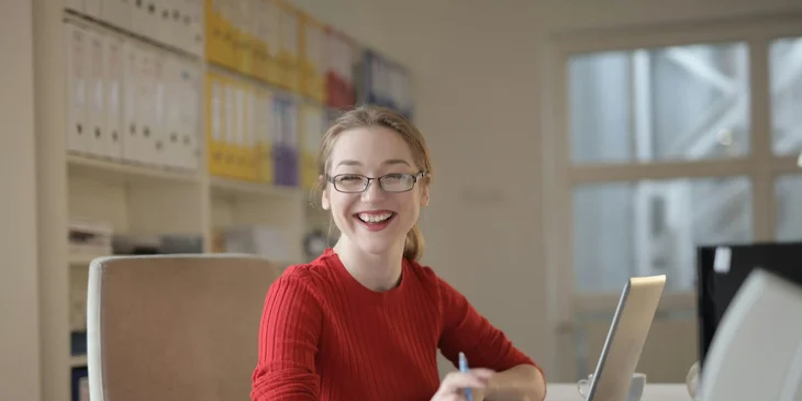 A woman in red sweater leaning in front of her laptop.
