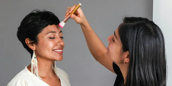 A makeup artist applying makeup to a woman's face.