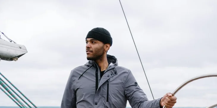 A maritime professional working and steering a sailboat.