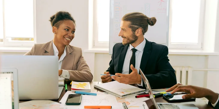 A woman sitting at a desk with a marketing team member.