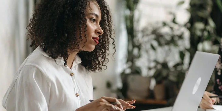 A woman working smiling and working on her laptop.