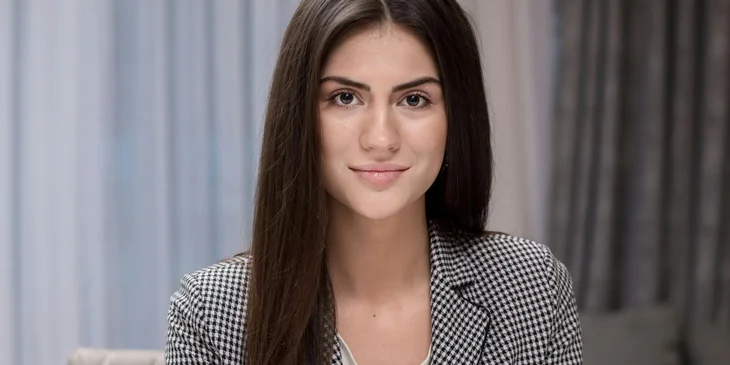 A woman sitting while smiling at the camera.