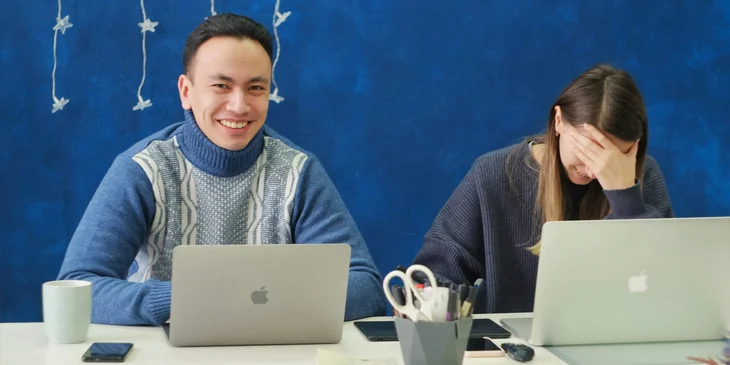 A man in a blue sweater using a laptop.