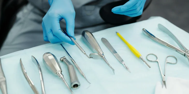 A medical equipment preparer assembling an instrument tray prior to surgery.