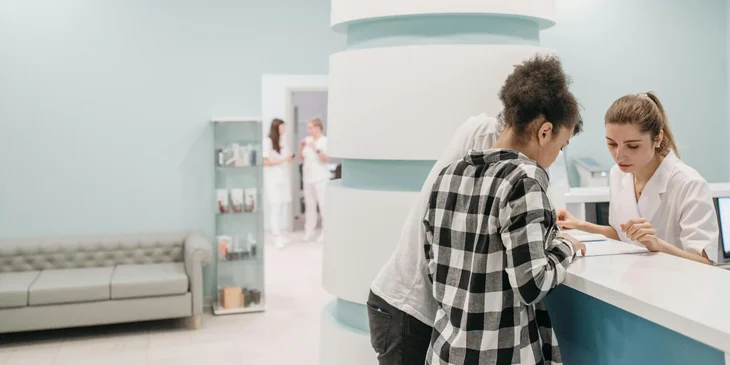 A medical office assistant helping a patient's family.