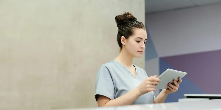 A medical receptionist waits at her desk for patients and visitors.