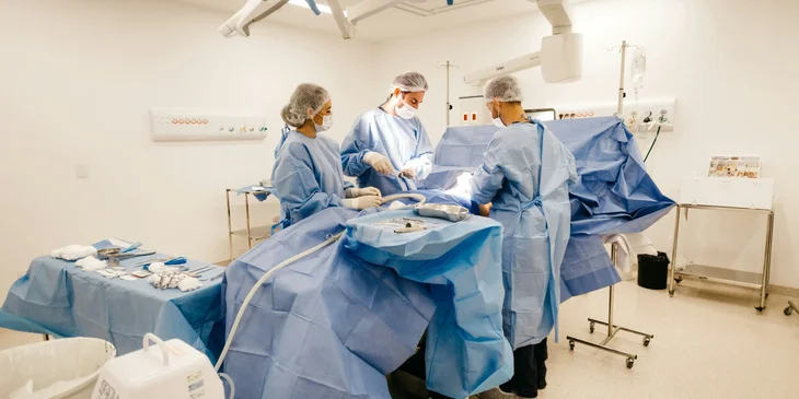 Medical specialists in blue scrubs working on a patient in the operating room.