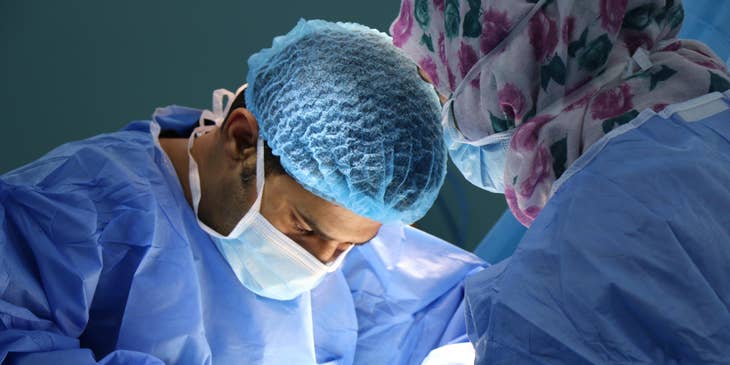 Medical specialists wearing blue scrubs at work in an operation room.