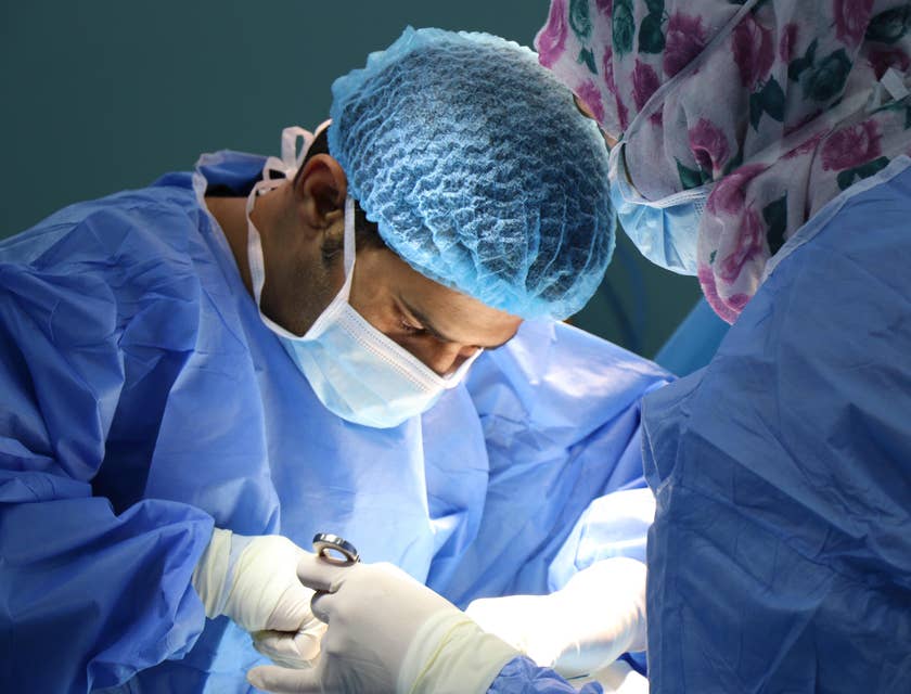 Medical specialists wearing blue scrubs at work in an operation room.