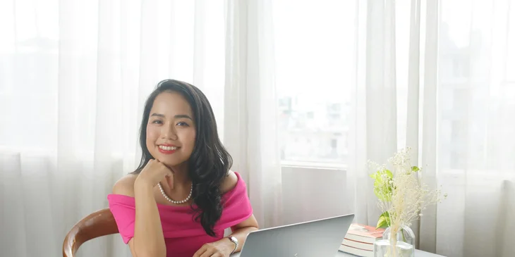 A woman sitting in front of a laptop smiling.