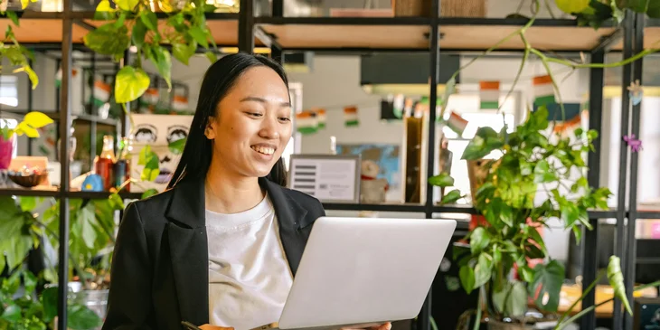 A woman standing in an office holding a laptop.