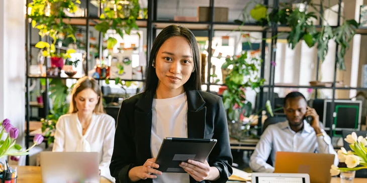 A woman standing in an office holding a tablet.
