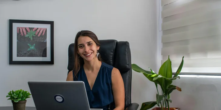 A woman in an office smiling in front of a computer.