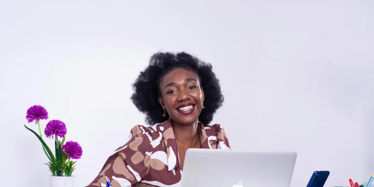 A woman sitting in front of a desk and a laptop.