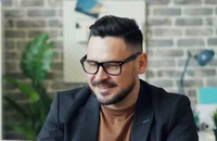 Masada oturarak laptopunu kullanan bir adam.