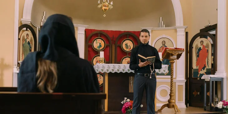 A priest in the middle of a church holding a bible.