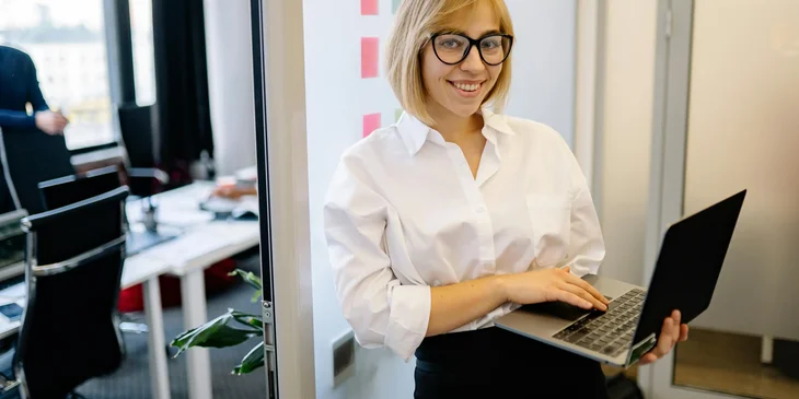 A woman standing while holding a laptop.