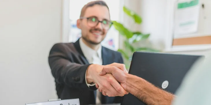 A mortgage broker shaking hands with a client to close a deal.