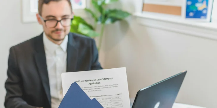 A client handing over the loan application form to a mortgage loan officer.