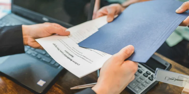 A client handing over the application loan documents.