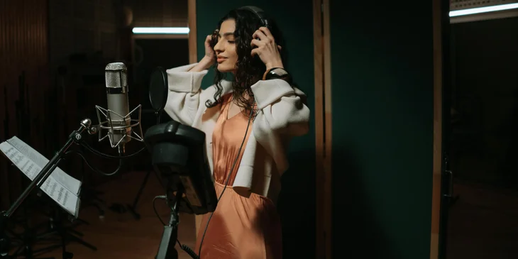 A woman recording a song in a recording studio.