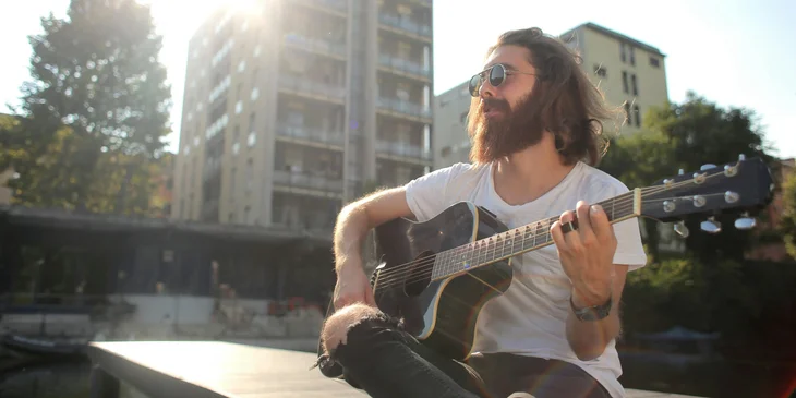 A man playing the guitar in an open area.